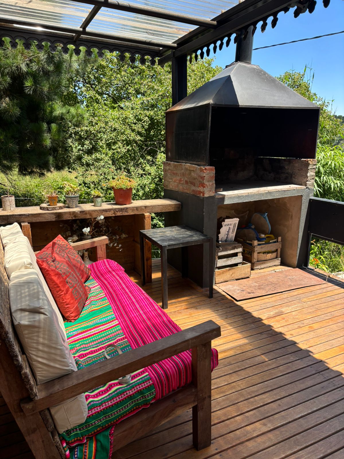 Galería techada con sillón exterior y parrilla